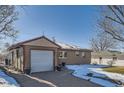 Front view of ranch home with attached garage and snow-covered landscaping at 5421 S Sherman St, Littleton, CO 80121