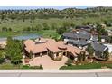 Breathtaking aerial view of a luxury home with a tile roof, lush landscaping, and golf course views at 7188 Raphael Ln, Littleton, CO 80125