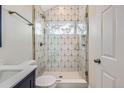 Modern bathroom with geometric tile in shower, glass door, and navy vanity at 3379 S Eliot St, Englewood, CO 80110