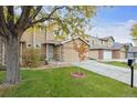 Two-story townhome with a tan exterior, attached garage, and landscaping at 9673 Ironton St, Commerce City, CO 80022