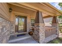 Cozy covered front porch featuring stone pillars, a wooden railing and room for seating at 24316 E Ottawa Ave, Aurora, CO 80016