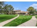 Townhome exterior featuring a beautiful green lawn and sidewalk at 9031 E Amherst Dr # D, Denver, CO 80231
