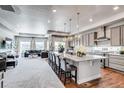 Open concept kitchen with a large granite island, pendant lighting, stainless steel appliances and gray cabinets at 16578 E 111Th Pl, Commerce City, CO 80022
