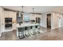 Well-appointed kitchen with white cabinets, stainless steel appliances, large island with seating, and stylish pendant lighting at 11885 W Katherine Ave, Lakewood, CO 80401