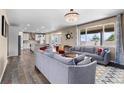 Open-concept living room with hardwood floors, large windows, and a view of the kitchen at 15100 Gaylord St, Thornton, CO 80602