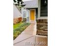 Inviting front entrance with a bright yellow door and stone accents at 6973 Summerset Ave, Longmont, CO 80504