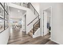 Open-concept foyer features sleek hardwood floors, a modern staircase with black metal railings, and abundant natural light at 7137 S Vandriver Way, Aurora, CO 80016
