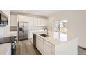 Bright kitchen with white cabinets, stainless steel appliances, and an island with a sink at 4823 Astor Pl, Brighton, CO 80601