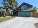 Charming two-story home featuring a green facade, brick accents, and a spacious driveway at 8296 S Reed St, Littleton, CO 80128