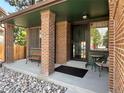 Inviting front porch with brick pillars, neutral colors, and a cozy seating area at 8296 S Reed St, Littleton, CO 80128