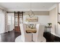 Elegant dining room featuring a rustic wood table, barn door, and stylish chandelier at 6072 Chester St, Denver, CO 80238