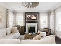 Bright living room with fireplace, ceiling fan, neutral color palette, and large windows at 6072 Chester St, Denver, CO 80238