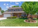 Traditional two-story home with brick accents, mature tree, and well-maintained front lawn at 7312 S Moore Ct, Littleton, CO 80127