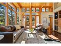 Cozy living room featuring wood ceilings, many windows, and leather furniture at 9041 Eastridge Rd, Golden, CO 80403