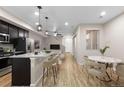 Open concept living and dining area with breakfast bar, modern finishes, and light wood-look floors at 23630 E 5Th Pl, Aurora, CO 80018