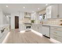Stylish kitchen boasts white cabinetry, modern appliances, gold hardware, and light wood flooring at 3281 Vivian Dr, Wheat Ridge, CO 80033