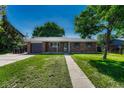 Inviting brick home with green shutters, manicured lawn, and an expansive front yard under a sunny sky at 7479 Pierce St, Arvada, CO 80003