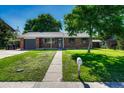 Quaint brick house with a well-kept lawn, sidewalk, and mature trees in a sunny neighborhood setting at 7479 Pierce St, Arvada, CO 80003