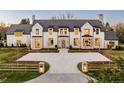 Beautiful exterior of white home with stone accents, paved driveway, professional landscaping, and dark roof at 20 Viking Dr, Cherry Hills Village, CO 80113
