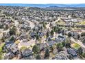 An aerial view showcases a residential neighborhood nestled among lush greenery and rolling hills at 286 Warwick Pl, Castle Pines, CO 80108