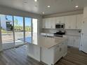 Bright kitchen with white cabinets, stainless steel appliances, a center island with a quartz countertop, and sliding glass doors at 17719 Prairie Peak Trl, Parker, CO 80134