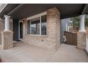 A covered front porch with brick pillars, a black front door, recessed lighting, and concrete flooring at 9250 Roadrunner Dr, Highlands Ranch, CO 80129