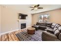 Comfortable living room featuring a fireplace, modern fan, and a dark leather couch at 7506 Sabino Ln, Castle Rock, CO 80108