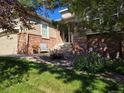 Welcoming home entrance featuring brick accents, a cozy seating area, and lush landscaping at 1033 Bramblewood Dr, Castle Pines, CO 80108