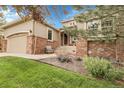 Home with inviting front porch with chair and red brick accents at 1033 Bramblewood Dr, Castle Pines, CO 80108
