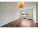Bright living room featuring rich wood flooring, large window, and a unique pendant light fixture at 1909 Iola St, Aurora, CO 80010