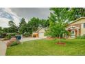Landscaped front yard with lush green grass and mature trees, showcasing a 'For Sale' sign at 8217 Club Crest Dr, Arvada, CO 80005