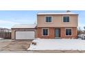 Charming two-story home featuring a brick facade, attached garage, and snow-covered front lawn at 1206 Baldwin Park Cir, Castle Rock, CO 80104