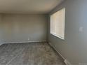 A cozy living room with neutral-toned walls, plush carpeting, and natural light streaming through the window at 4785 Estes St, Wheat Ridge, CO 80033