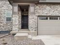 Inviting entryway features a stone facade, covered porch, and a stylish front door with side window and two car garage at 559 Homestead Ave, Brighton, CO 80601