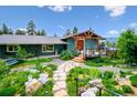 Inviting home exterior featuring a spacious deck, landscaped yard, and stone walkway at 6565 Marshmerry Ln, Evergreen, CO 80439