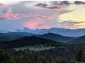 Breathtaking mountain view with a colorful pink sunset sky over lush green hills at 6565 Marshmerry Ln, Evergreen, CO 80439