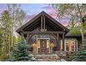 Detailed wood-clad entrance featuring a covered porch and stone accents, framed by lush greenery at 215 Royal Tiger Rd, Breckenridge, CO 80424