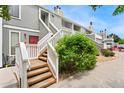 Exterior view of building with well-maintained landscaping, wooden stairs and red doors at 1160 S Monaco Pkwy # 6, Denver, CO 80224