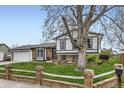 Inviting home featuring a lush front yard, mature trees, and a unique brick and wood fence at 10020 Bryant St, Denver, CO 80260