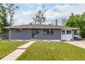 Inviting single-level home with gray brick, a manicured lawn, and a welcoming pathway to the front entrance at 2612 Meadowbrook Dr, Denver, CO 80221