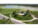 Aerial view of a large park with mature trees, walking paths, a playground, and a lake beyond at 6411 W 82Nd Dr, Arvada, CO 80003