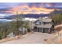 Beautiful gray home boasts an attached two car garage with a scenic mountain view and sunset sky at 26456 Sweetbriar Trl, Evergreen, CO 80439