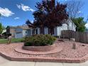 Beautifully landscaped front yard with a vibrant red tree, decorative rock features, and a well-maintained lawn at 16308 E Wyoming Dr, Aurora, CO 80017