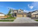 Two-story house with stone and beige siding, two-car garage, and landscaping at 16198 E 111Th Pl, Commerce City, CO 80022