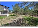 Expansive backyard offers a blend of wooded areas and open lawn space for outdoor recreation at 1673 Woodmoor Dr, Monument, CO 80132