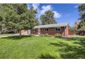 Landscaped front yard of brick home with green lawn and mature trees casting dappled shadows on a sunny day at 3205 Moorhead Ave, Boulder, CO 80305