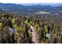An aerial view showing the property's location nestled among trees and a scenic roadway at 11650 Baca Rd, Conifer, CO 80433