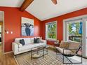 A vibrant living room features a vaulted ceiling, a cozy sofa, and access to the deck at 11650 Baca Rd, Conifer, CO 80433