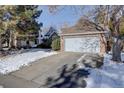 Brick ranch home with attached garage and snow-covered yard at 6055 W Warren Pl, Lakewood, CO 80227