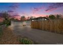 Home exterior with driveway and fenced yard under a beautiful sunset sky at 3015 Pierce St, Wheat Ridge, CO 80214